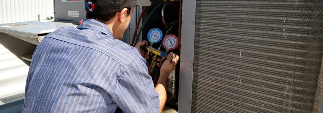 HVAC technician servicing a condenser unit in Olive Branch
